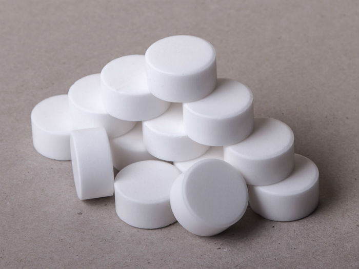 Используя промышленные системы водоочистки и водоподготовки для фильтрации и умягчения воды в быту и производстве, соли используют в процессах водоподготовки (пищевой или технологической). Кроме того, эта соль, вероятно, молотая (мелкая или грубая).  В большинстве случаев использование таких солей в системах водоподготовки не вполне оправдано. Это связано с тем, что обычная молотая поваренная соль имеет ряд существенных недостатков.  Достаточно перечислить некоторые из них, чтобы понять, что использование обычной поваренной соли в системах водоподготовки крайне нежелательно.  Во-первых, использование таких солей приводит к образованию толстого слоя накипи на дне отопительных котлов и баков в очень короткие сроки. Во-вторых, из водяных фильтров системы водоподготовки вымываются ионообменные смолы и реагенты, -третьих, на внутренних стенках водопроводных труб образуются отложения, когда нерастворившиеся кристаллы соли налипают на частицы ионообменной смолы. в них появляются трещины. В большинстве случаев это приводит к блокировке ионообменных свойств.  Таблетированная соль в основном используется для регенерации ионообменных смол в системах водоподготовки для умягчения воды. Процесс умягчения воды — очистка воды от кальция широко применяется в фармацевтической, пищевой, химической промышленности и энергетике, подробнее здесь.  Соль таблетированная для систем водоподготовки – пищевая соль высшего сорта (NaCl) без добавок йода и ферроцианида калия (добавки против затвердевания соли), прессованная в таблетки или подушечки.  Такие таблетированные соли бесцветны, не имеют запаха, практически негорючи и совершенно невзрывоопасны. Таблетированную соль в большинстве случаев упаковывают в полипропиленовый мешок с полиэтиленовым вкладышем по 25 кг.  Использование таблетированной соли вместо обычной поваренной соли обеспечивает следующие преимущества для вашей домашней системы очистки воды:  Таблетированная соль имеет гораздо большую площадь поверхности, чем такое же количество обычной поваренной соли. В результате расход в системе приготовления примерно на 30% меньше, чем у обычной соли. Соль в таблетках обладает «растворяющим эффектом» и при растворении солевых таблеток в солевом баке растворимый осадок не образуется, а в некоторых случаях даже приводит к выходу из строя оборудования системы водоподготовки. Поступая при той же жесткости, таблетированная соль растворяется равномерно до образования регенерационного раствора. Это исключает дополнительное ручное или механическое перемешивание.  На основании вышеперечисленных качеств к таблетированным солям предъявляются следующие требования:  Таблетированные соли для систем водоподготовки должны быть максимально чистыми. Чтобы очистка бытовой воды была эффективной, содержание NaCl в ней должно быть не менее 99,5 %. Таблетки соли медленно растворяются после падения в воду и не распадаются сразу. Всем этим отвечают только соляные таблетки, изготовленные из поваренной соли «экстра» и без добавления йода и ферроцианида калия.  Таблетированные соли для систем водоподготовки пользуются большой популярностью благодаря использованию при их производстве в компаниях новейших немецких технологий и отечественного оборудования, специально разработанного для производства таблетированных солей.  Кроме того, сырьем для таблетирования соли является специально очищенная пищевая соль «Экстра», которую перед употреблением тщательно промывают. В этом случае цена будет немного выше обычной соли.  Производитель пищевой соли специально изменил технологию изготовления пищевой соли «Экстра», используемой в производстве таблетированной соли для водоочистного оборудования. В нем используется только чистая соль, без добавок и полностью чистый хлорид натрия.